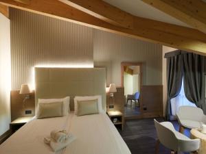 a bedroom with a large white bed with two towels on it at X Alp Hotel in Pozza di Fassa