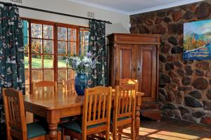 uma sala de jantar com uma mesa de madeira e cadeiras em Stonecutters Lodge em Dullstroom