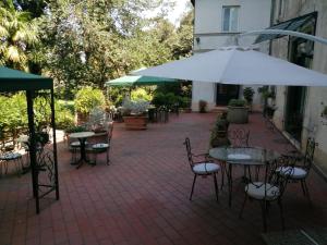 a patio with tables and chairs and an umbrella at VILLA LA DOGANA in Lucca