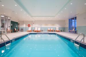 - une piscine dans un hôtel avec des chaises et des tables dans l'établissement Holiday Inn Edmonton South - Evario Events, an IHG Hotel, à Edmonton
