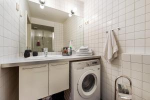 a white bathroom with a washing machine and a sink at Tjuvholmen I, As Home in Oslo