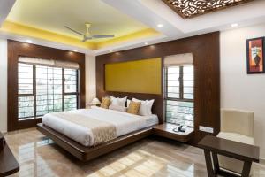 a bedroom with a bed and a desk and windows at Cygnett Style Tania's in Siliguri