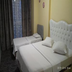 2 camas en una habitación de hotel con sábanas y almohadas blancas en The Tuyap Rainbow Suites, en Beylikduzu