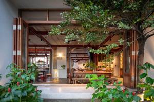 an entrance to a restaurant with tables and trees at Hotel Gahn - SHA Plus in Khao Lak