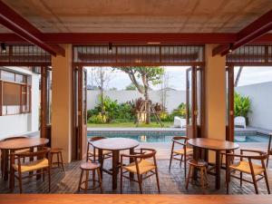 a restaurant with tables and chairs and a swimming pool at Hotel Gahn Khao Lak in Khao Lak