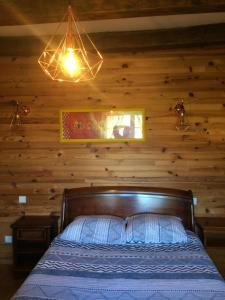 ein Schlafzimmer mit einem Bett mit einer Holzwand in der Unterkunft Le Maquis in Charmes