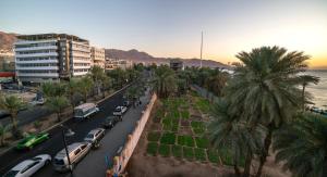 a city street with cars and palm trees and the ocean at Nairoukh Hotel Aqaba in Aqaba