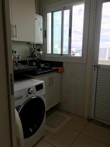 a kitchen with a washing machine and a window at Cobertura Beira Mar in Capão da Canoa