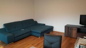 uma sala de estar com um sofá azul e uma televisão em RELAX in der Natur 2 Zimmer Apartment - im Grünen - Ruhelage em Kennelbach