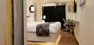 a bedroom with a bed and a desk with a computer at Hotel surya dev residency in Bangalore