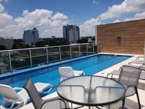 a balcony with a table and chairs and a swimming pool at START Villa Morra Rent Apartments in Asunción