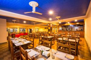 Hotel Royal Safari في سوراها: مطعم بطاولات وكراسي خشبية وسقف