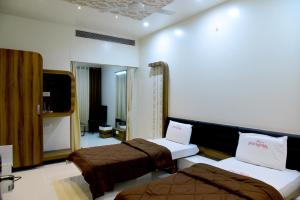 a hotel room with two beds and a television at Hotel Pushpak in Satara