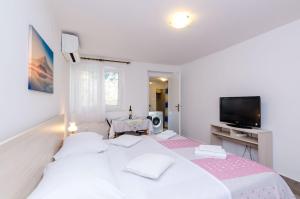 a white bedroom with a large bed and a tv at Guesthouse Matusic in Dubrovnik