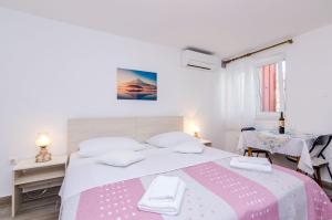 ein weißes Schlafzimmer mit einem großen Bett und 2 Tischen in der Unterkunft Guesthouse Matusic in Dubrovnik + 23 Fotos