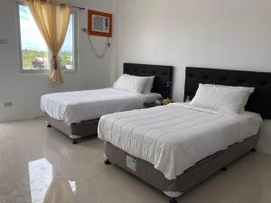 two beds sitting in a bedroom with a window at Arriyus Apartelle in Maya