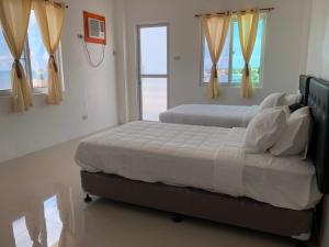 2 Betten in einem Schlafzimmer mit 2 Fenstern in der Unterkunft Arriyus Apartelle in Maya