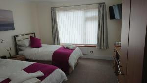 um quarto de hotel com duas camas e uma janela em Rose Vean Bed & Breakfast em Helston