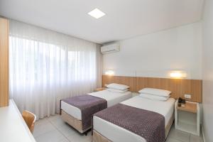 a hotel room with two beds and a window at Saint Emilion by Atlantica in Curitiba