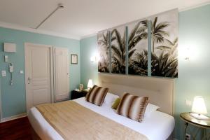 a bedroom with a bed with a painting on the wall at Hotel Les Pasteliers in Albi