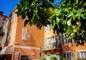 un bâtiment orange avec un arbre devant lui dans l'établissement Hôtel restaurant Oasis, à Nice