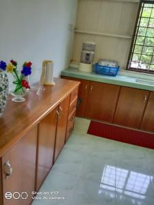 a kitchen with wooden cabinets and a counter with flowers on it at OPRO S&S Homestay Pagoh Malay Only in Muar