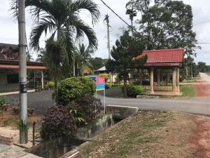 a street with a building and a palm tree and a sign at OPRO S&S Homestay Pagoh Malay Only in Muar
