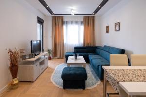 ein Wohnzimmer mit einer blauen Couch und einem Fernseher in der Unterkunft Trebinje Star in Trebinje
