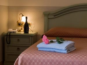 a bed with a bottle of wine and a towel on it at Hotel Louis II in Ciampino