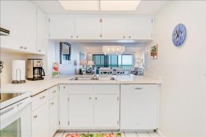 a kitchen with white cabinets and a sink at Sea Oats 215 Apartment in Boca Grande