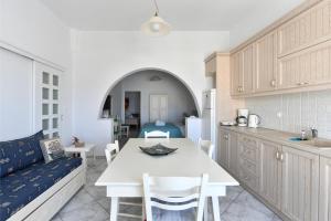 a kitchen and living room with a table and a couch at White Rooms Paros in Naousa