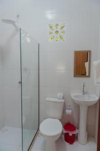 a white bathroom with a toilet and a sink at Aruá Observação de aves e natureza in Praia do Forte