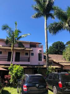 two cars parked in front of a house with palm trees at Pousada Y-Goá in Bertioga