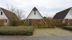 una casa antigua con techo inclinado y dos casas en Vrijstaande woning te Vlagtwedde en Vlagtwedde