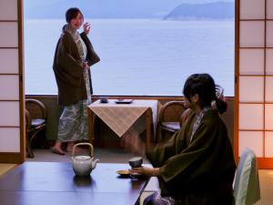 two people sitting at a table in front of a window at Wakayama Kada Onsen Kada Kaigetsu (ex. Azumaya Seaside Hotel) in Wakayama