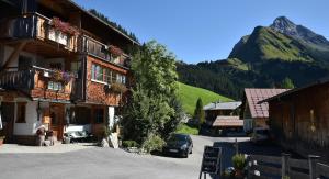 un edificio en un pueblo con una montaña en el fondo en Biobauernhof Gehrnerhof am Arlberg en Warth