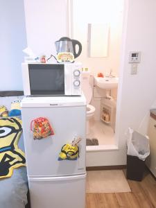 a kitchen with a microwave on top of a refrigerator at 林林の民宿-関空直達、minion room 小黄人主题房 in Osaka
