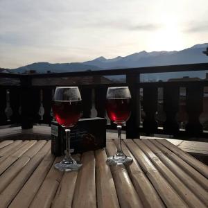 Dois copos de vinho tinto numa mesa de madeira. em Relax Dobrinishte em Dobrinishte