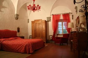 a bedroom with a red bed and a chandelier at Villa Guadagni Cappelli in Arezzo +62 photos