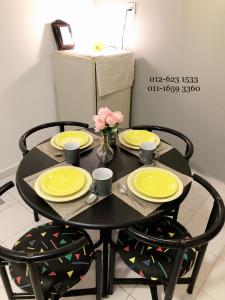 Una mesa negra con platos amarillos y flores. en Bukit Tinggi 1 Hati guesthouse en Bukit Tinggi