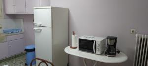 a kitchen with a table with a microwave and a refrigerator at The comfy flat in Athens