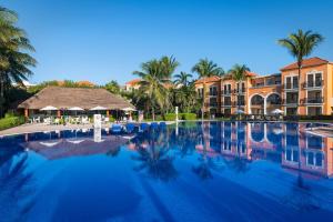 Una gran piscina con palmeras y edificios. en El Beso Adults Only at Ocean Coral & Turquesa All Inclusive, en Puerto Morelos