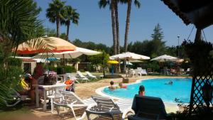 a swimming pool with people sitting in chairs and umbrellas at B&B Villa Anastasia Club in Mesagne