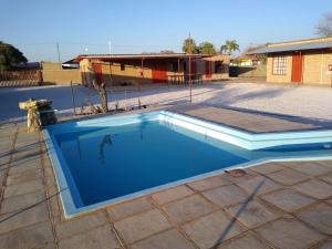 a blue swimming pool in a yard with a building at Stop 'n Stay Otavi Rest Camp in Otavi