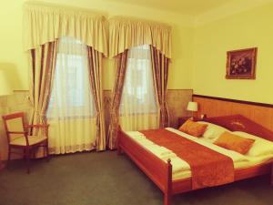 um quarto com uma cama, uma cadeira e janelas em River Star Hotel em Praga