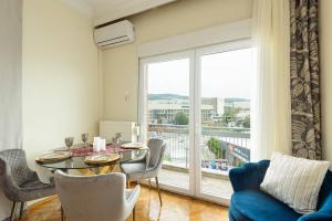 una sala da pranzo con tavolo, sedie e una grande finestra di Endless View City Center Condo a Salonicco