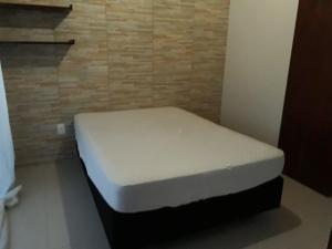 Cama blanca en una habitación con pared en Duplex com vista do mar!, en Itapema