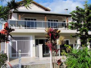 a white house with a balcony and palm trees at Duplex com vista do mar! in Itapema
