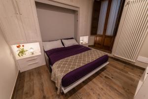 a bedroom with a bed with purple sheets and a window at Alla cava Orvieto in Orvieto