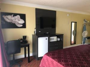ein Hotelzimmer mit einem Bett und einem Flachbild-TV in der Unterkunft Americas Best Value Presidents Inn on Munras in Monterey